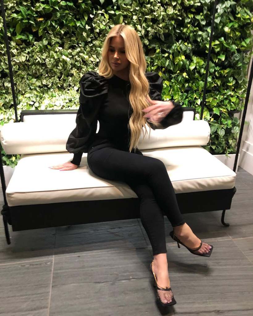 Kim Zolciak in a black outfit sitting with her legs crossed