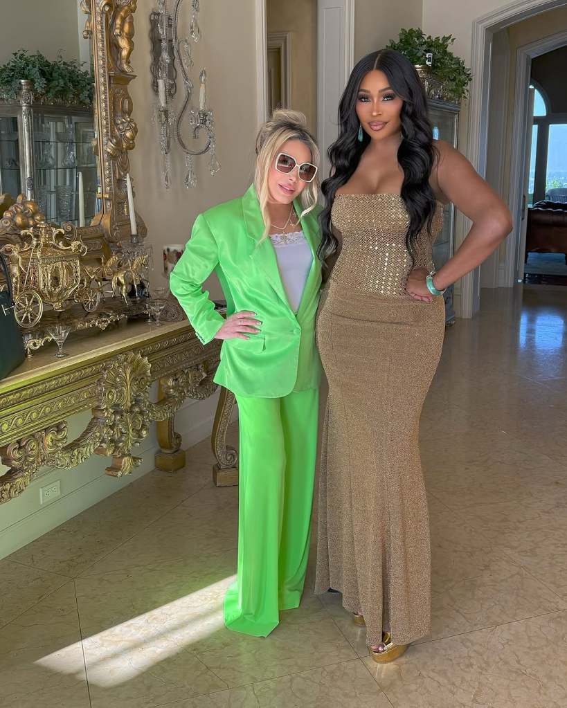 Adrienne Maloof in a green suit posing with Cynthia Bailey, who is wearing a brown dress