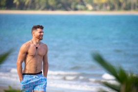Cashel Barnett in blue swim trunks walking across the beach on Love Island USA