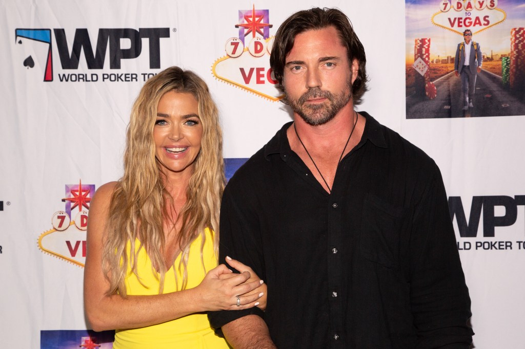 Denise Richards in a yellow dress holding onto Aaron Phyper's arm