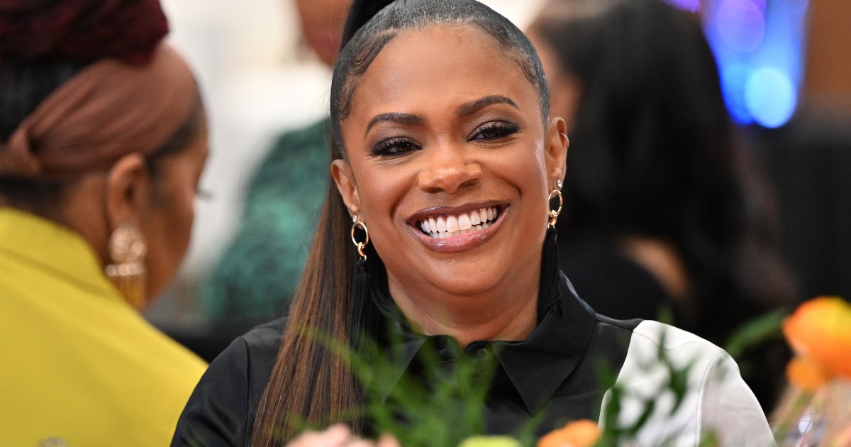 Kandi Burruss in a black shirt and smiling on an episode of RHOA