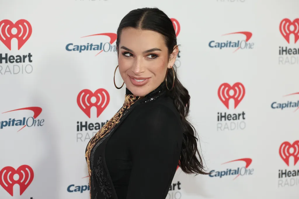 Ashley Iaconetti at iHeartRadio Jingle Ball, wearing black, and doing an over the shoulder pose