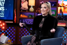 Erika Jayne on Watch What Happens Live, shrugging her shoulders, and wearing a black outfit with fur