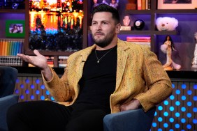 Brock Davies in a yellow blazer, holding his hand out on Watch What Happens Live