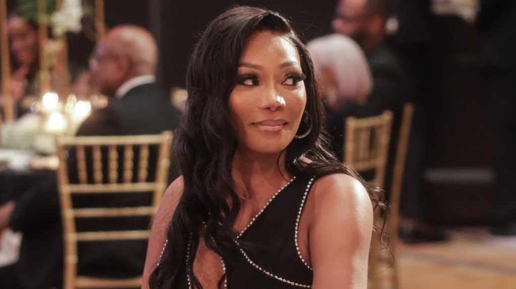 Angela Oakley sitting at a table and wearing a black dress during the RHOA Season 16 finale