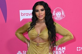 Mia Thornton in a yellow dress posing with her hands on her hips in front of a pink backdrop