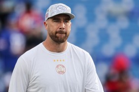 Travis Kelce wearing a white shirt and biting his lip