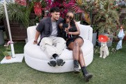 Kenny Rodriguez and JaNa Craig sitting on a white couch at Coachella 2025