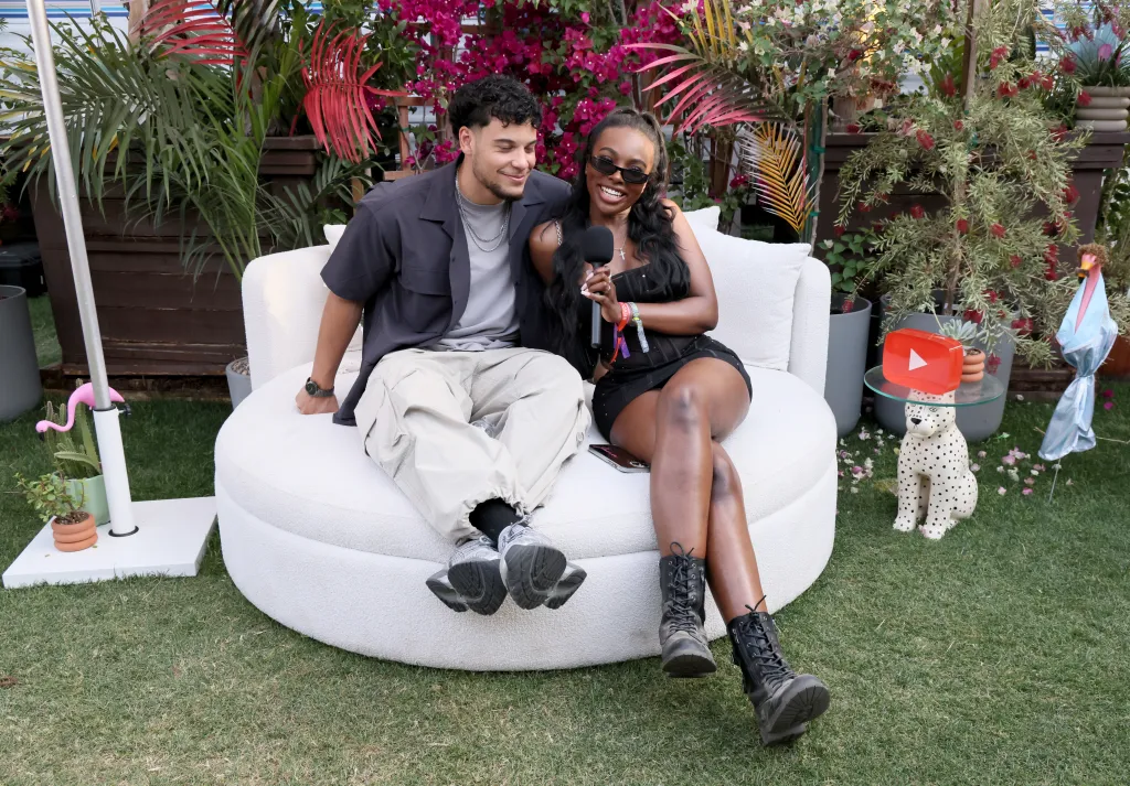 Kenny Rodriguez and JaNa Craig sitting on a white couch at Coachella 2025