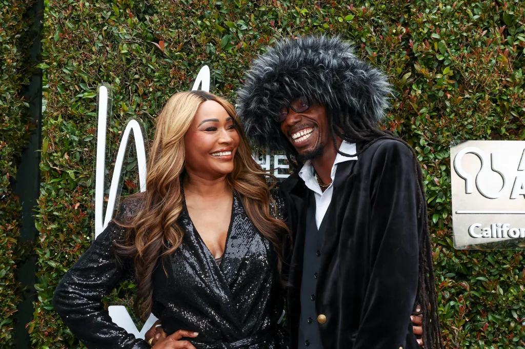 Cynthia Bailey and LePrince waring all black and posing in front of a green backdrop