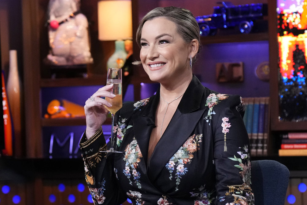 Hannah Ferrier on Watch What Happens Live holding a glass of champagne 