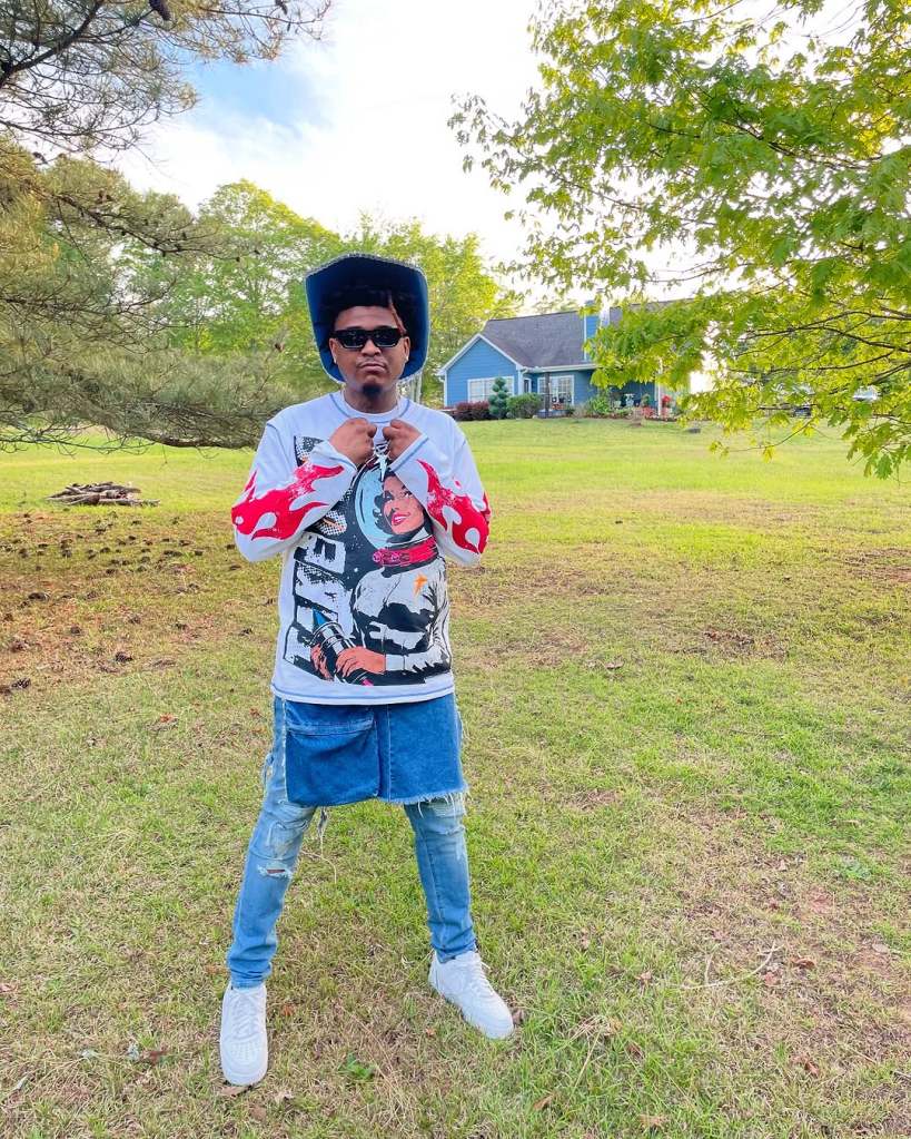 T-Hood posing in front of a home