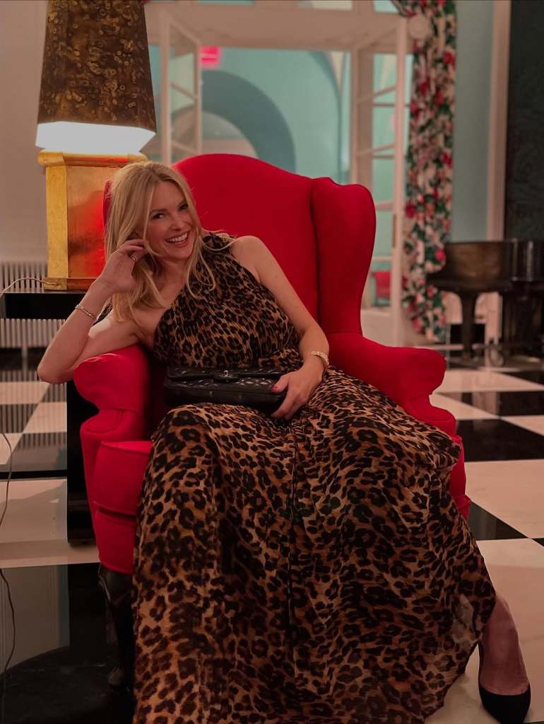 Kelley Wolf in a cheetah print dress sitting in a large red chair