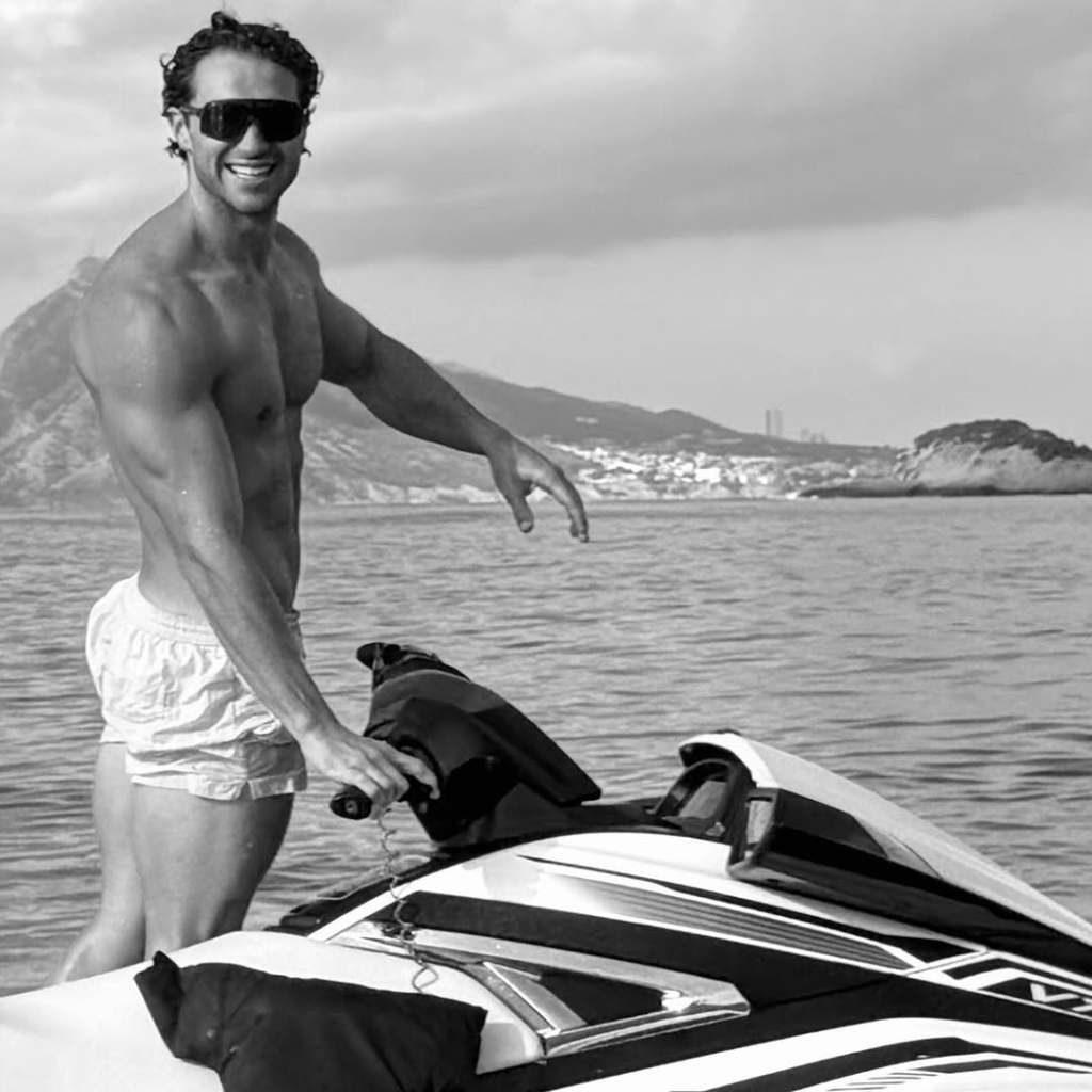 Black and white photo of Joe Bradley, shirtless and on a jet ski