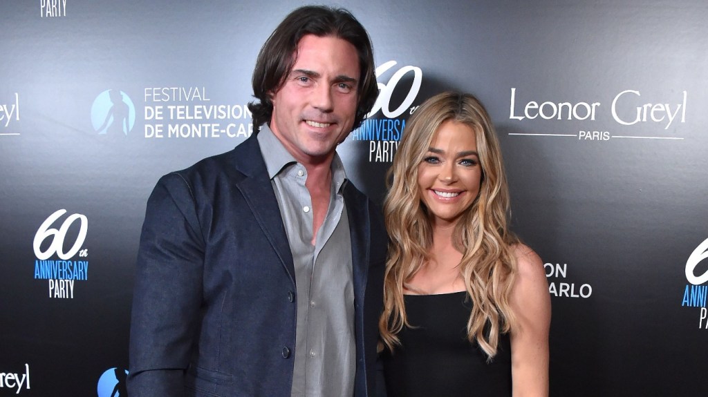 Aaron Phypers in a blue blazer and Denise Richards in a black dress posing together at a red carpet