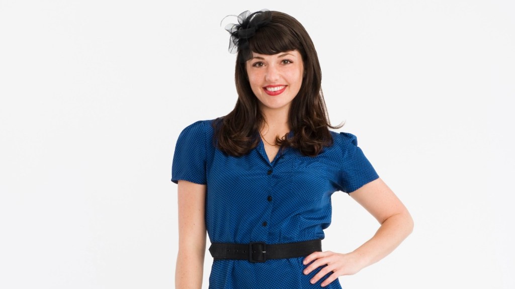 Kenley Collins in a blue dress standing with her hand on her hip for Project Runway Season 5