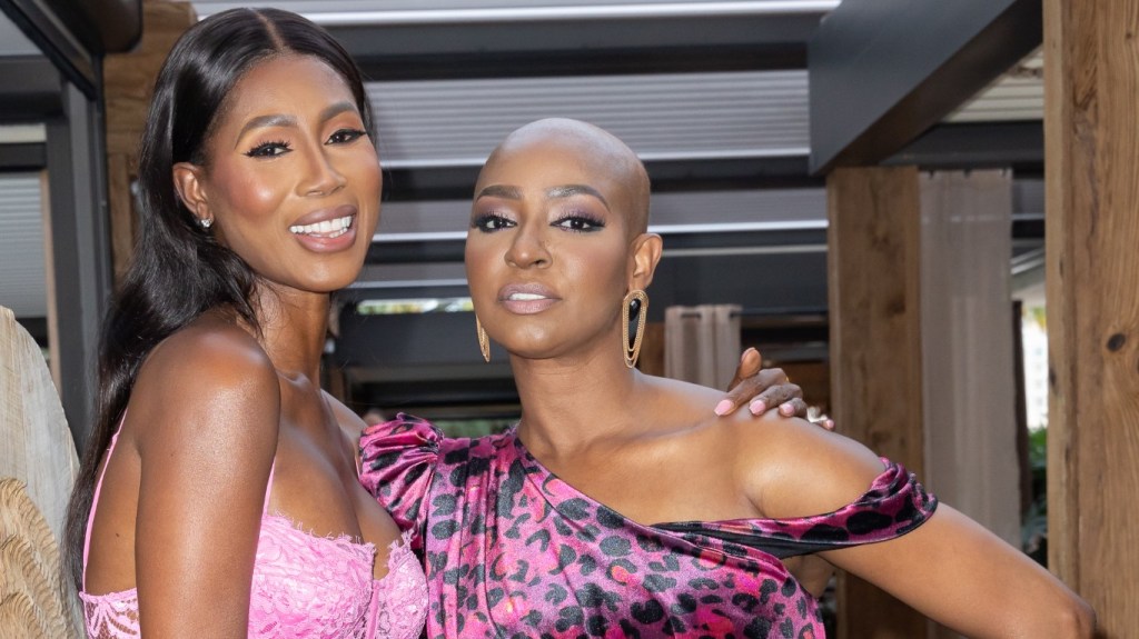Guerdy Abraira and Kiki Barth posing in pink dresses with their arms around each other