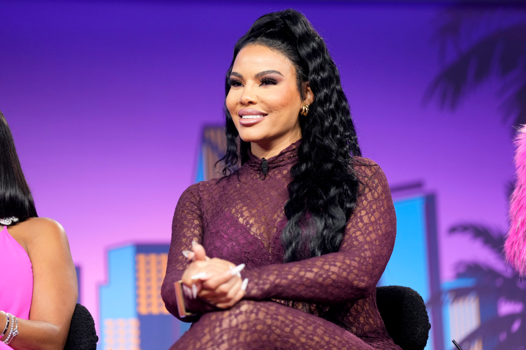 Mia Thornton in a purple jumpsuit sitting on s chair on stage at Bravo Fan Fest Miami