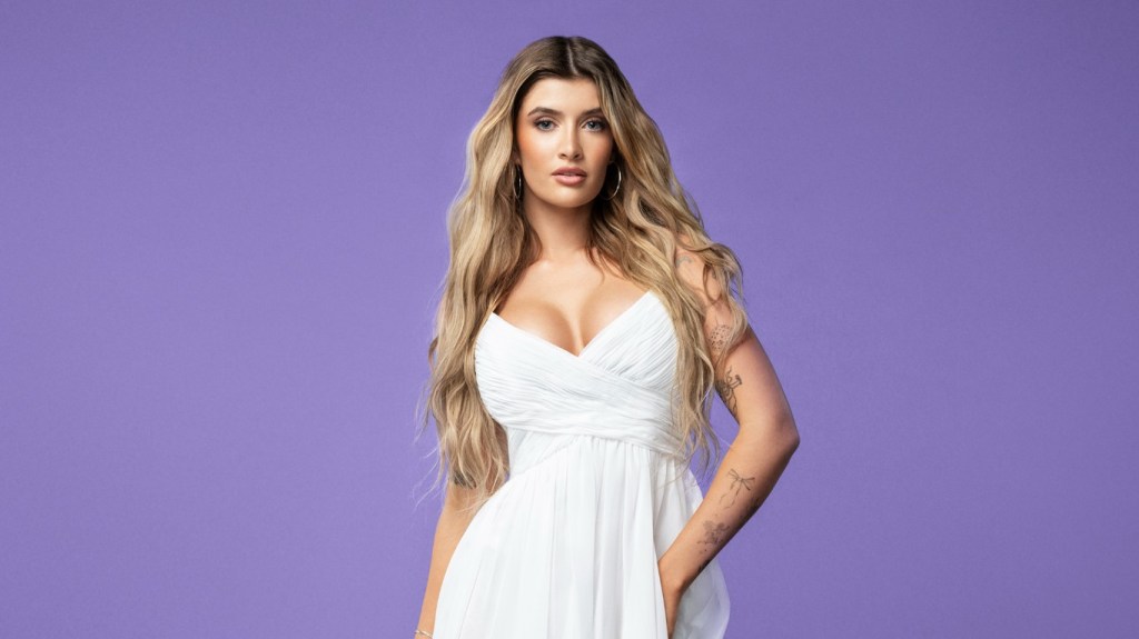 Sami Sheen in a white dress in front of a purple background