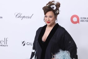 Jennifer Tilly in a black robe with feathers and white flowers in her hair