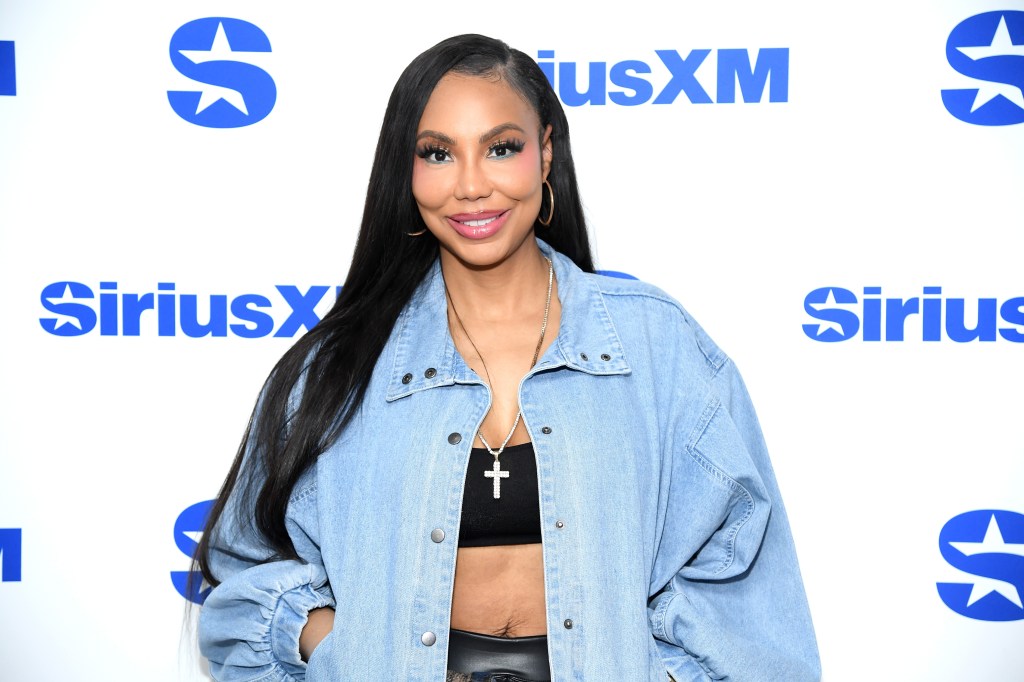 Tamar Braxton in a denim shirt and black crop top posing at SiriusXM studios