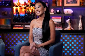 Katie Ginella in a sparkly silver dress sitting with her legs crossed and grinning on Watch What Happens Live