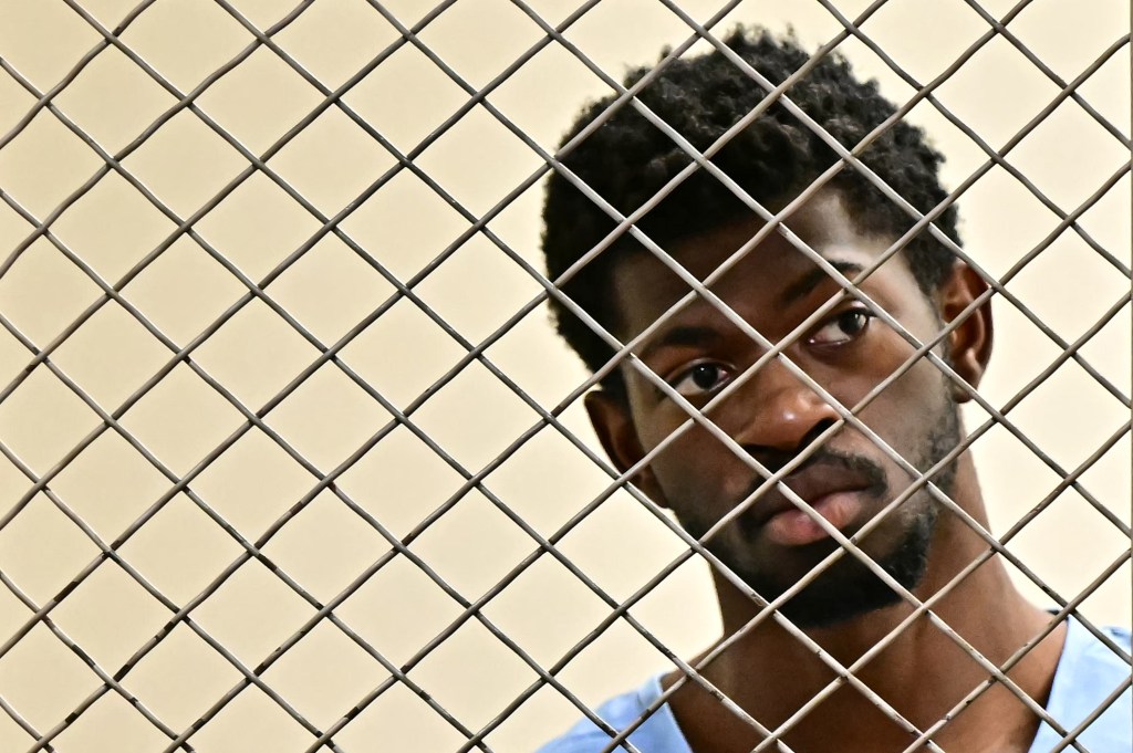 Lil Nas X in a jail cell wearing a blue jumpsuit