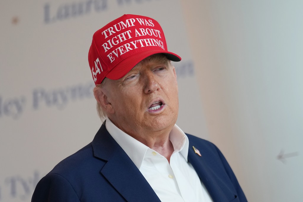 Donald Trump speaking to reporters while wearing a hat that says "Trump Was Right About Everything"