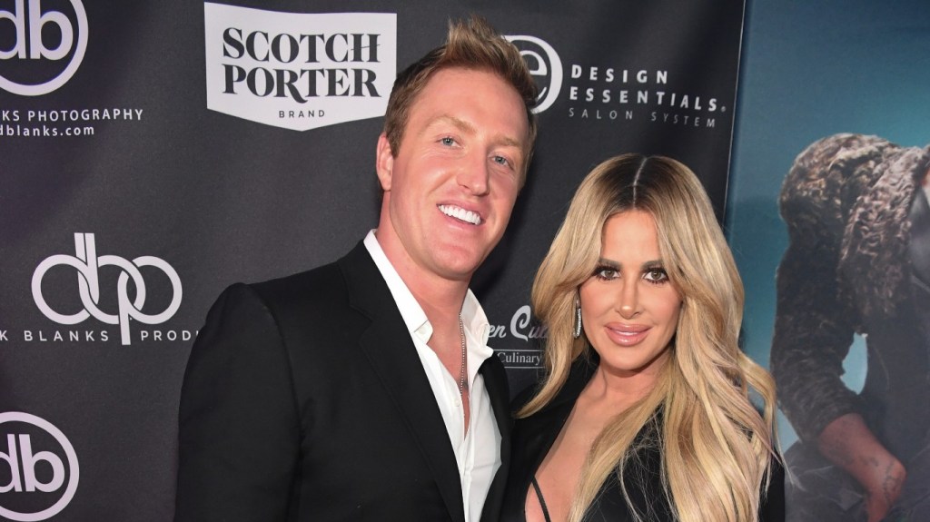 Kroy Biermann in a black suit posing with Kim Zolciak, who is wearing a black dress