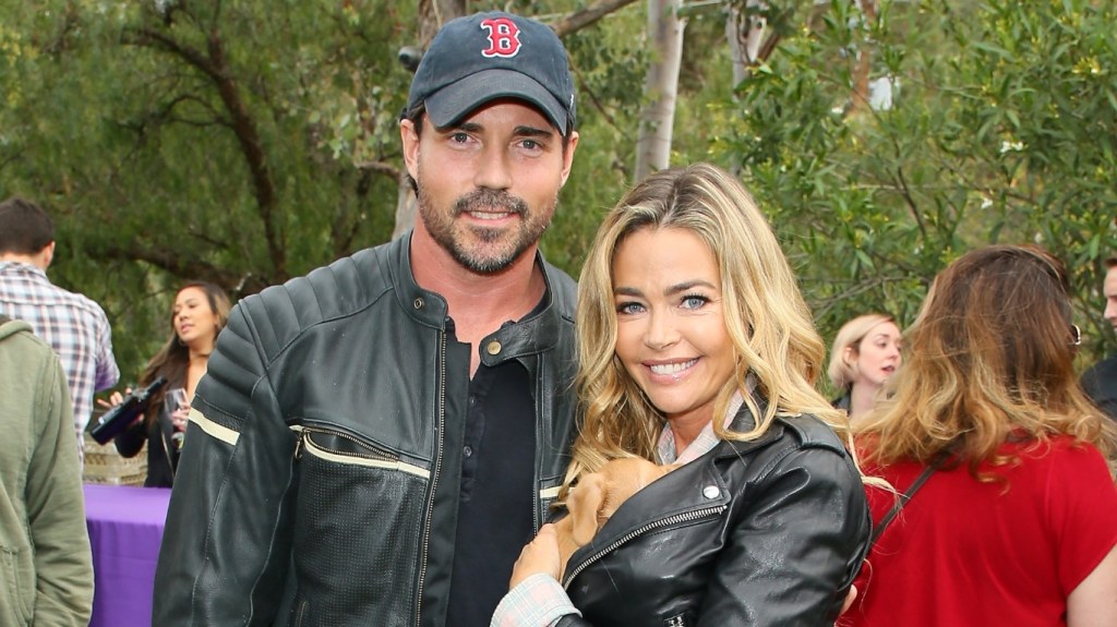 Denise Richards holding a dog and posing next to Aaron Phypers