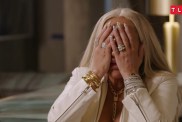 Darcey Silva in a white coat covering her face with her hands
