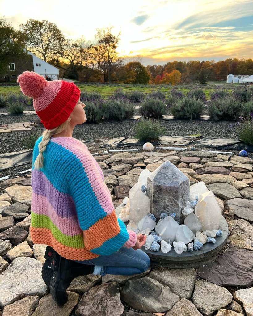 Yolanda Hadid in a colorful sweater, kneeling in the middle of her lavender farm