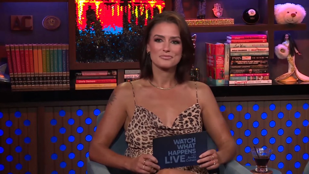 Aesha Scott in a cheetah-print dress on Watch What Happens Live, holding up a note card