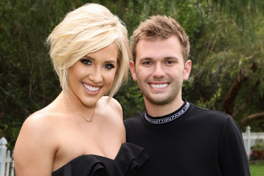 Savannah and Chase Chrisley wearing black and posing outside in front of trees