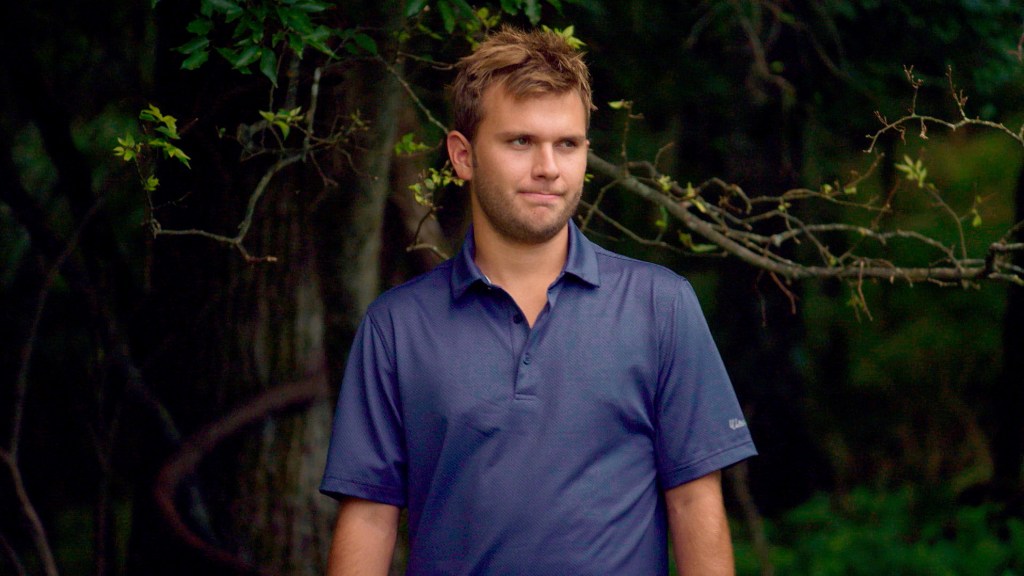 Chase Chrisley in a blue polo standing in front of a tree