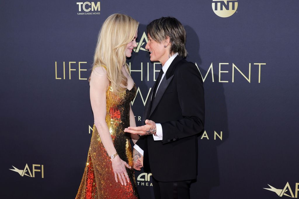 Nicole Kidman in a gold dress standing face-to-face, inches apart from Keith Urban