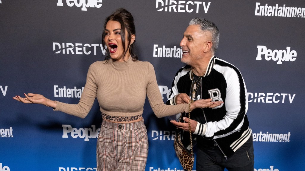 Golnesa Gharachedaghi with her mouth open and holding her arms out while Reza Farahan stands to the side