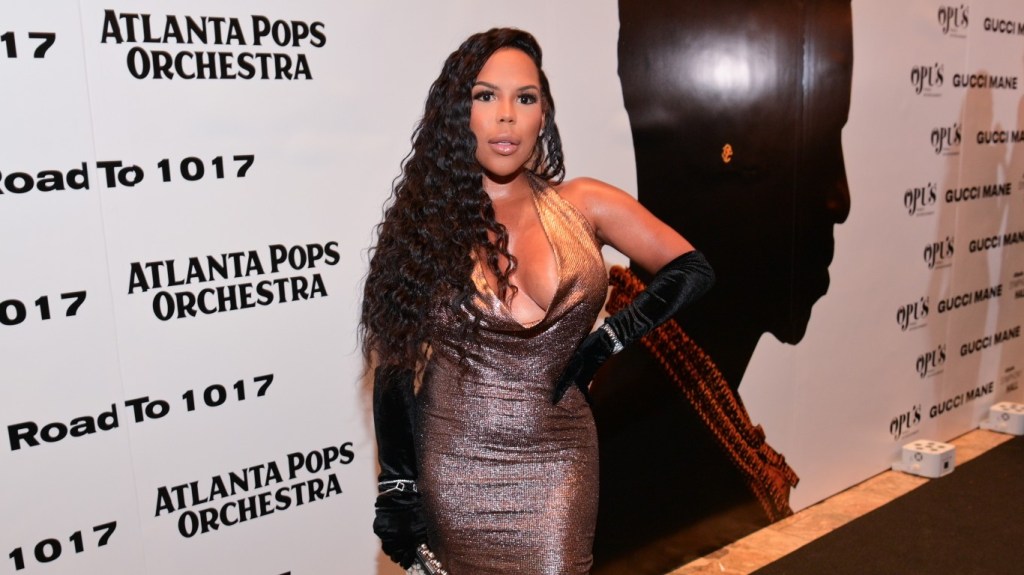 Kelli Ferrrel in a silver dress and black gloves, posing with her hand on her hip