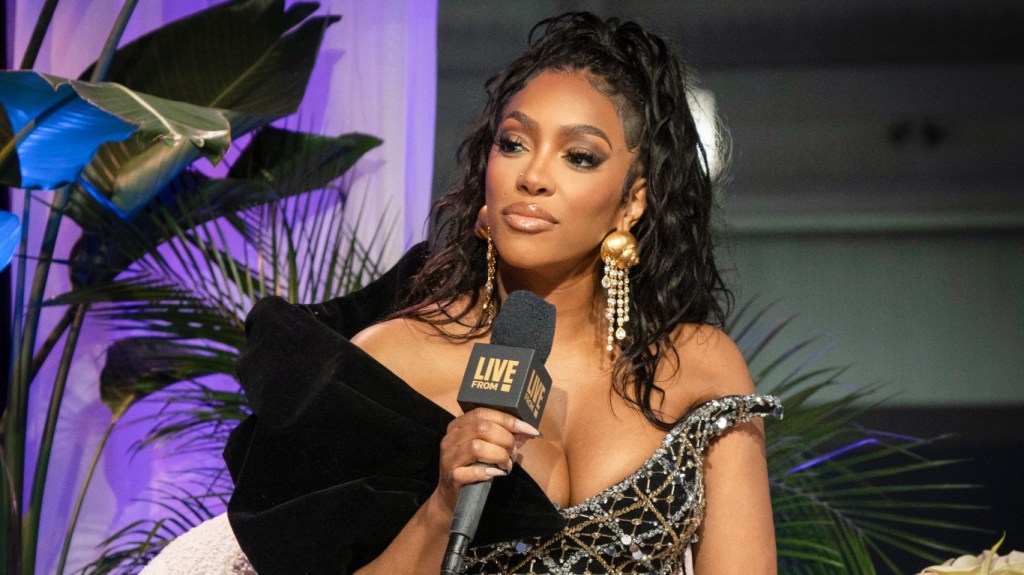 Porsha Williams in a black and silver dress, holding a black microphone