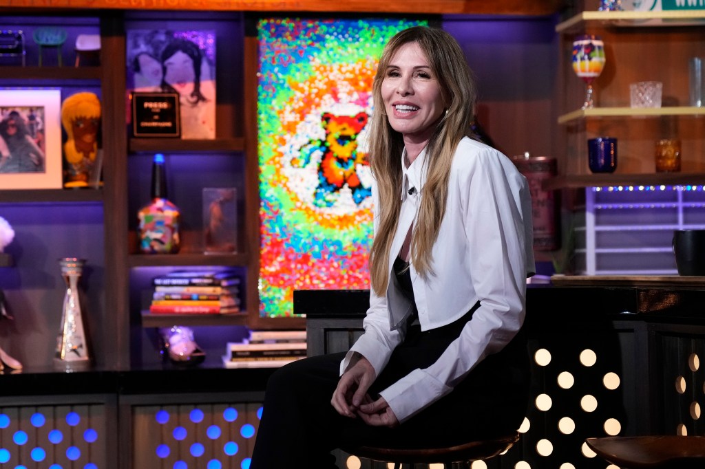 Carole Radziwill in a white jacket sitting next to the bar on Watch What Happens Live