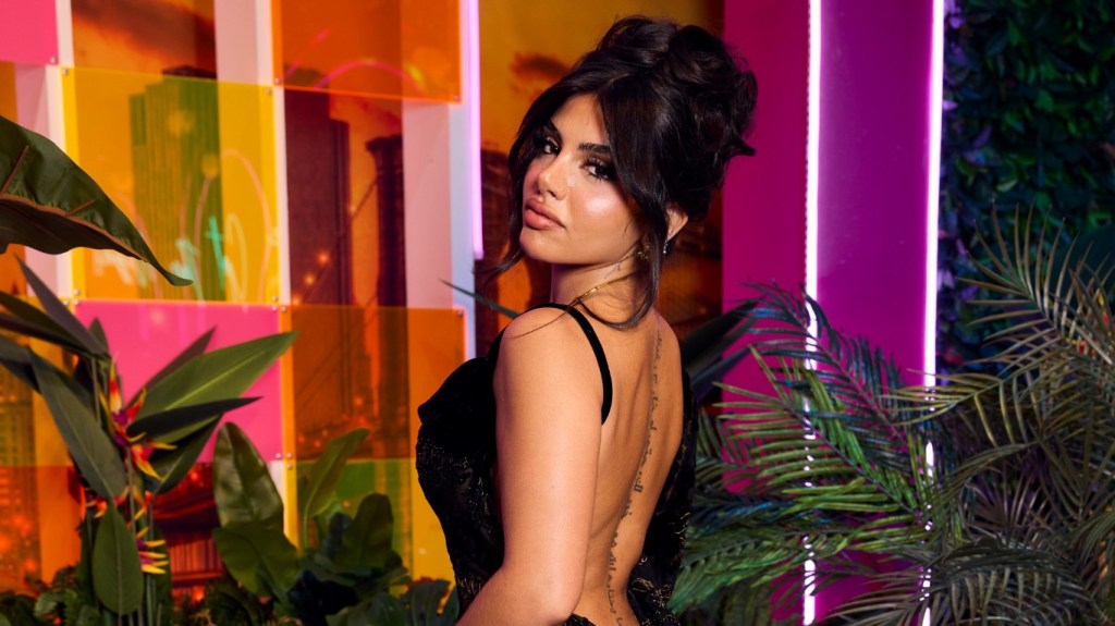Huda Mustafa in a black dress doing an over the shoudler pose at the Love Island USA reunion
