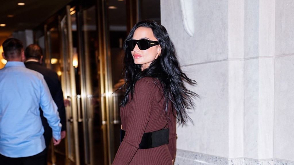 Demi Lovato in a red jumpsuit doing an over the shoulder pose outside of Watch What Happens Live