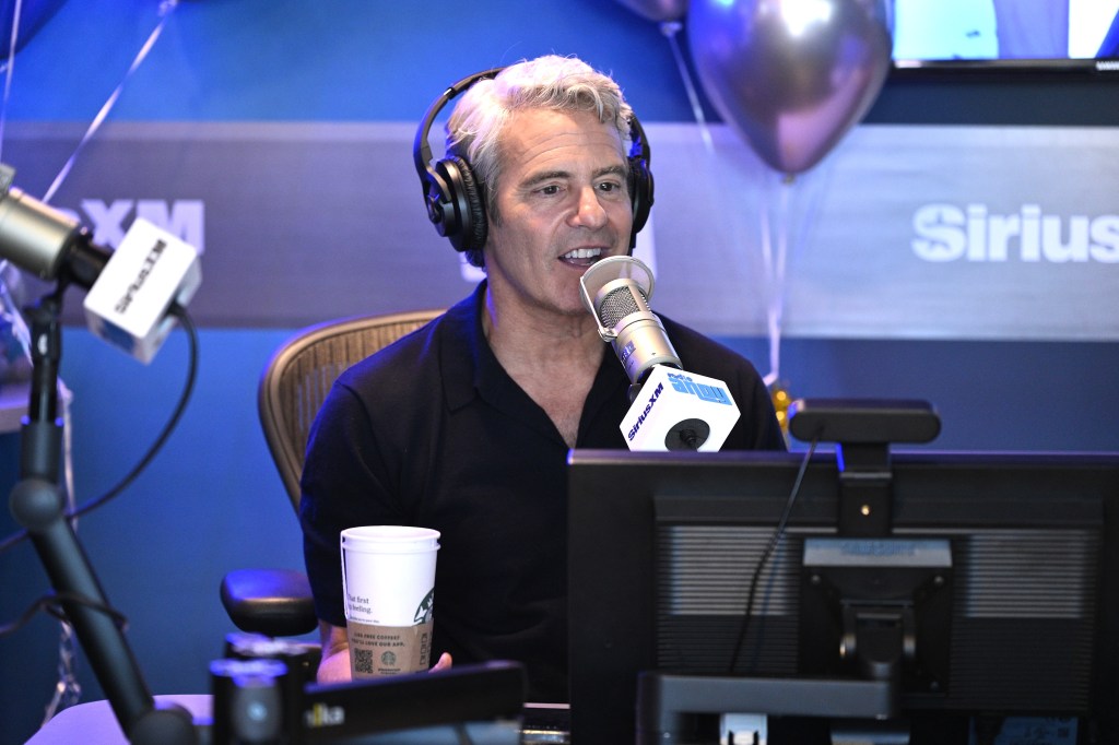 Andy Cohen in a black polo shirt behind the microphone at SiriusXM studios