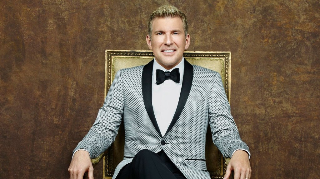 Todd Chrisley in a grey suit sitting in a gold chair for Chrisley Knows Best Season 4