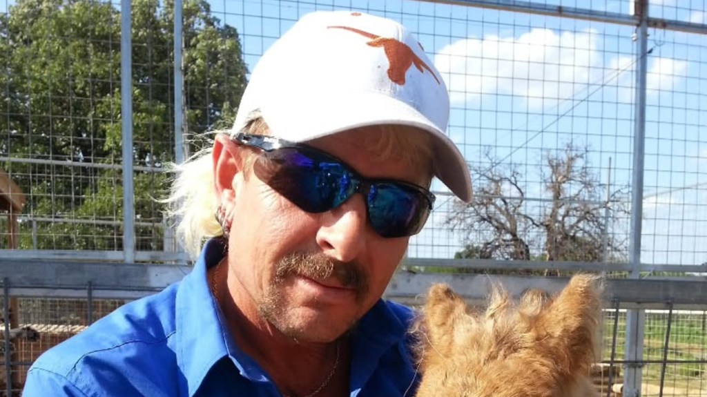 Joe Exotic in a white Longhorns hat, posing with an animal