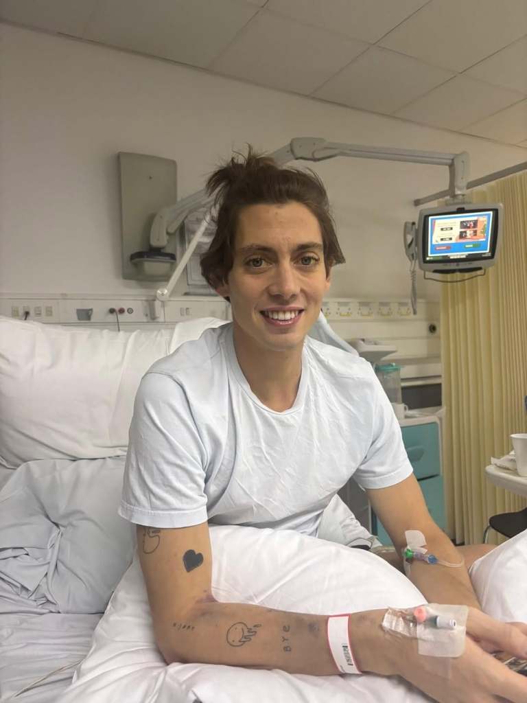 Sam Vanderpump sitting in a hospital bed, hooked up to machines