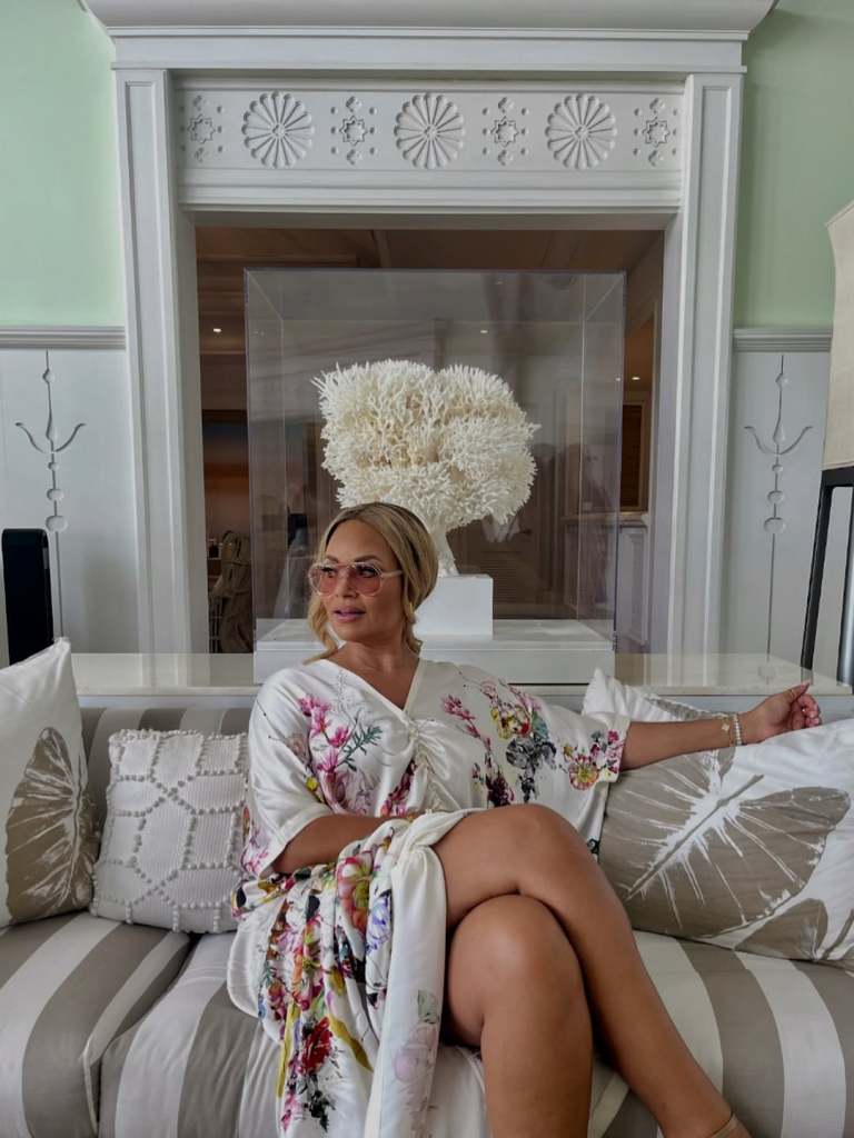 Gizelle Bryant in a floral robe sitting with her legs crossed on a couch