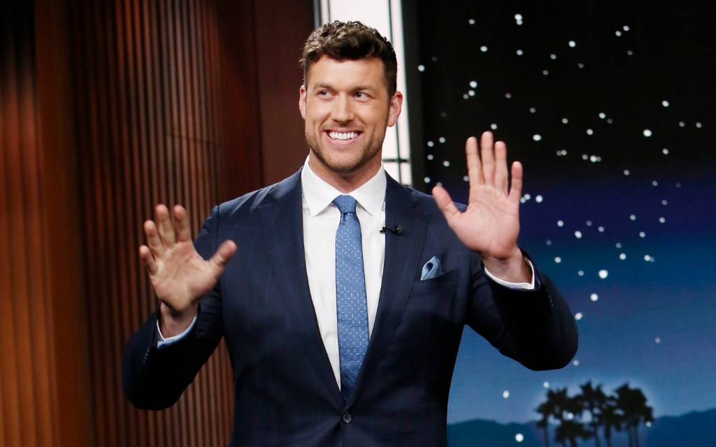 Clayton Echard in a blue suit waving his hands on Jimmy Kimmel Live