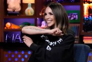 Scheana Shay in a black hoodie on Watch What Happens live showing off her "It's all happening" tattoo