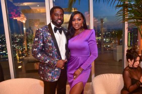 Wendy and Eddie Osefo posing in purple outfits in front of a window overlooking Los Angeles
